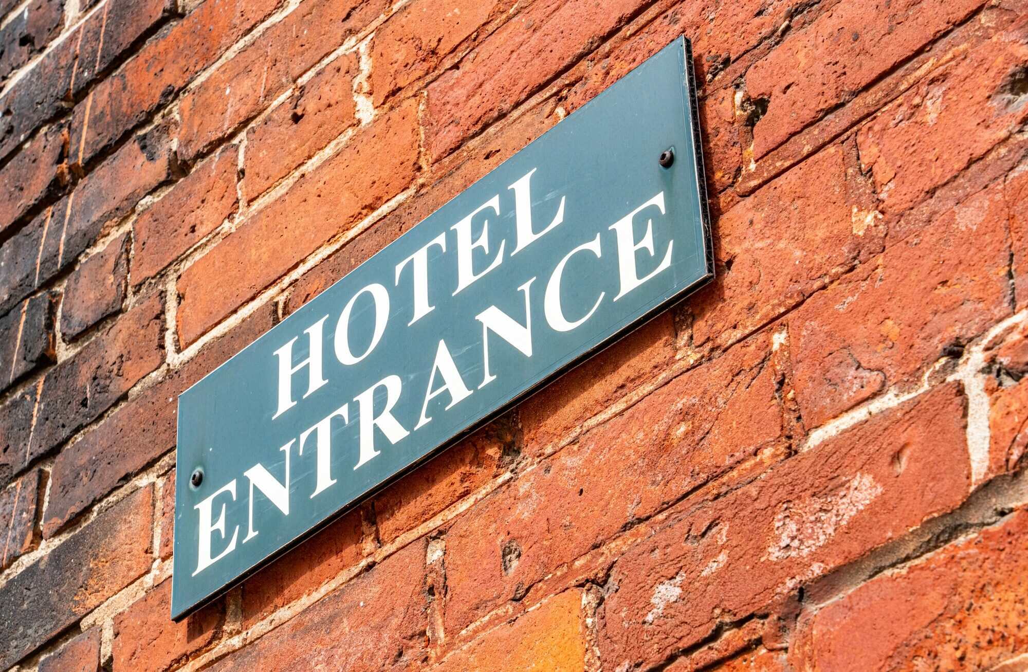 Hotel entrance identification plaque mounted on a brick wall