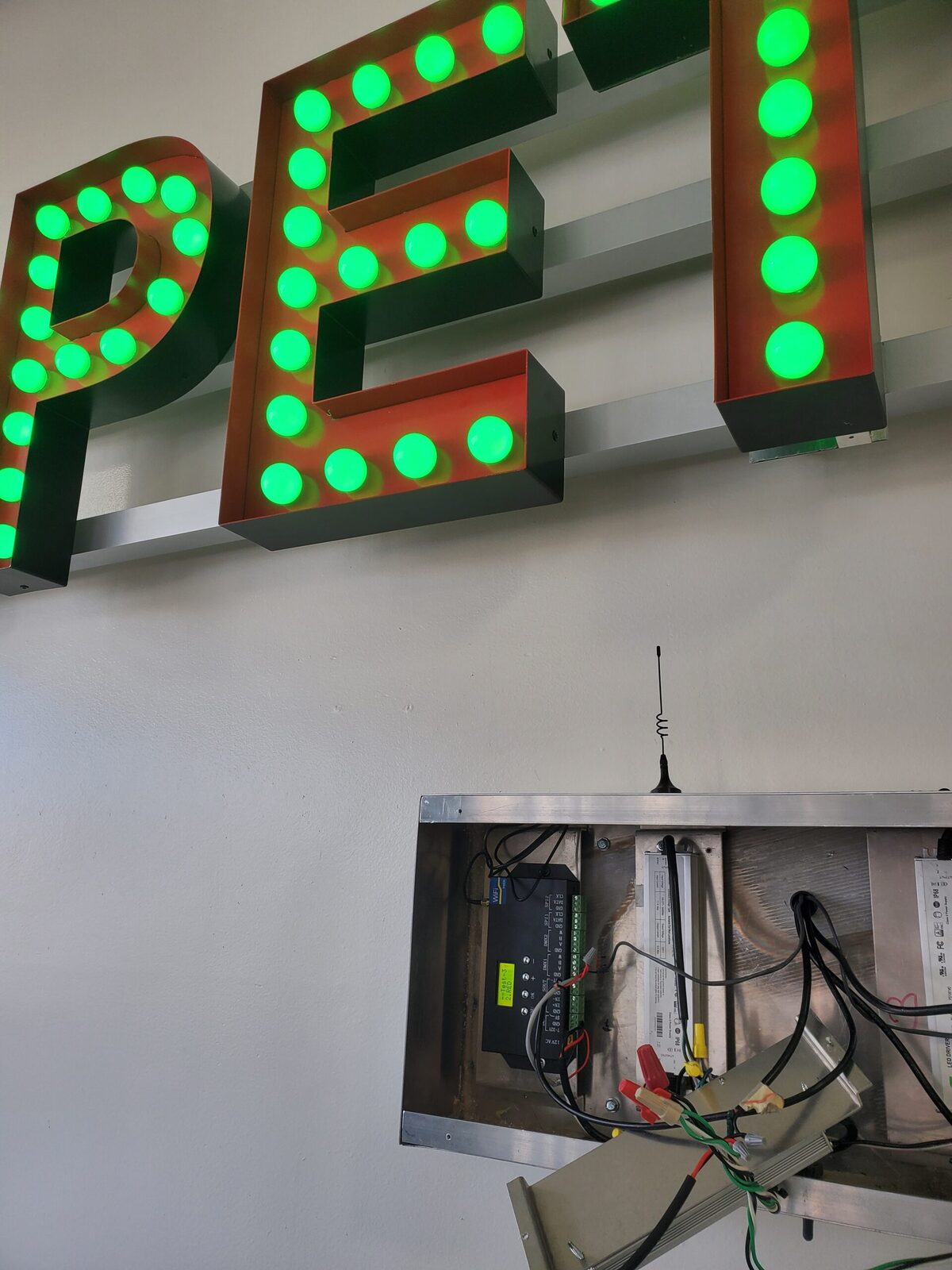 Open-face channel letters with rows of exposed green marquee bulbs