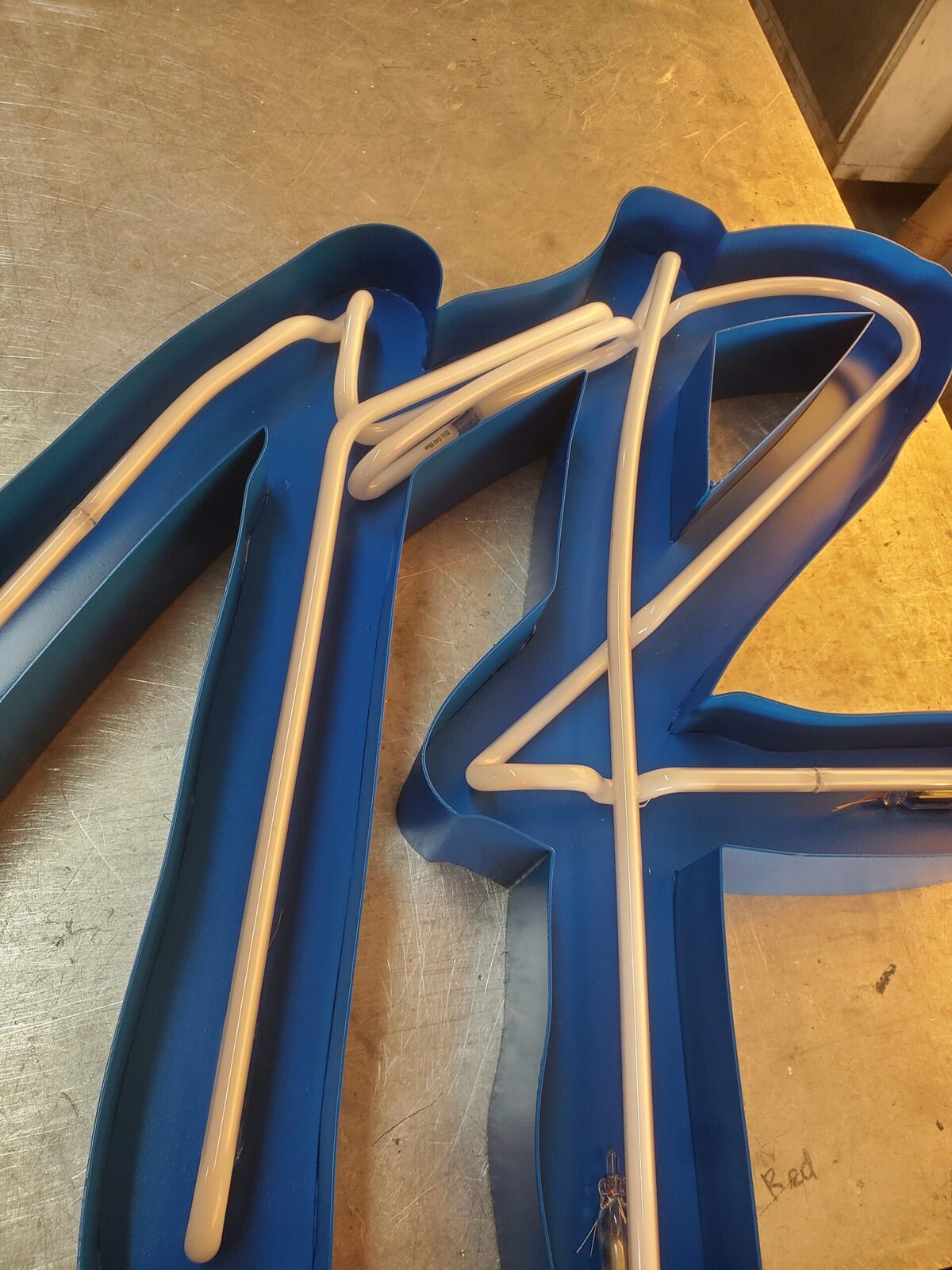 Navy open-face channel letter with neon tubing fitted inside the open can