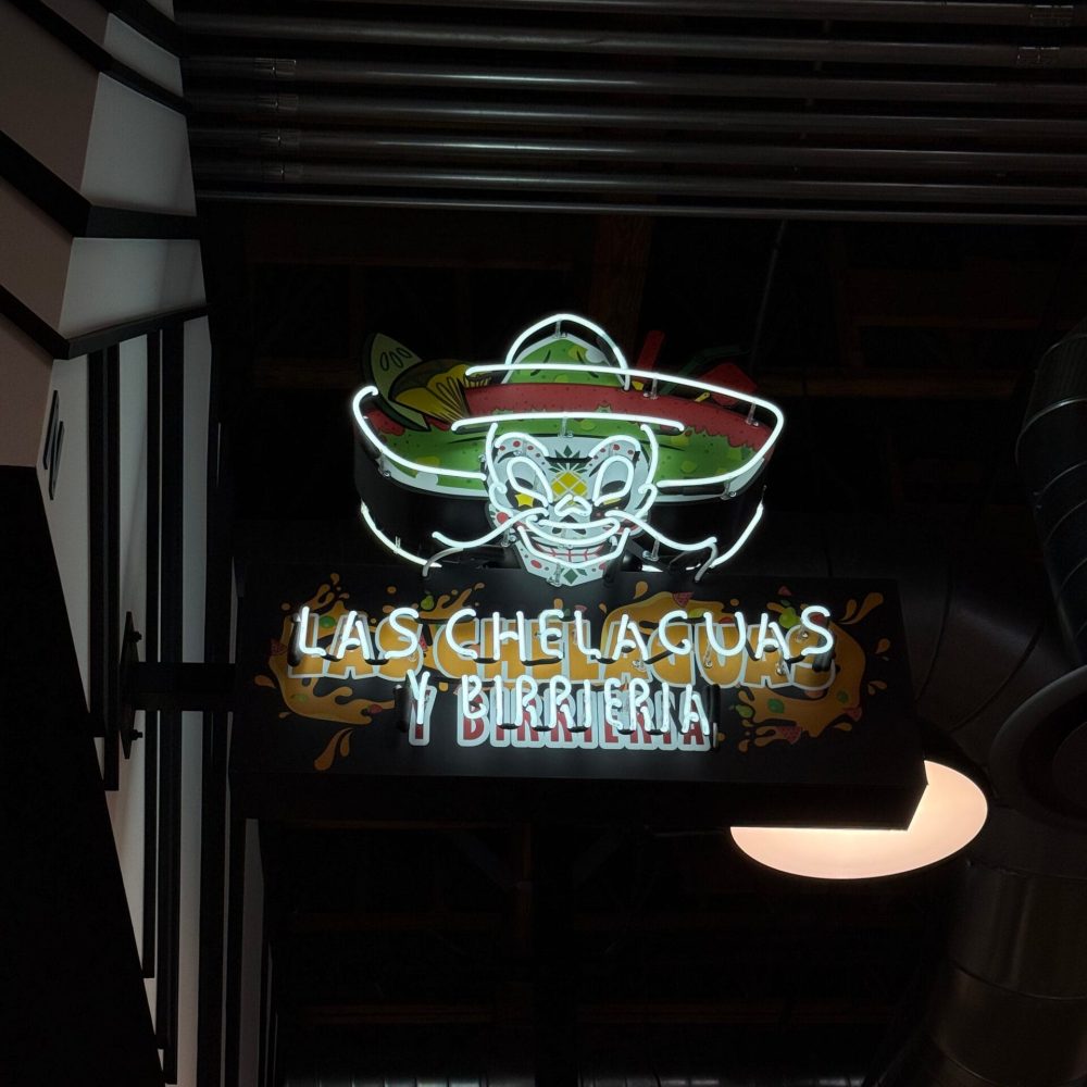 Illuminated blade sign mounted on a neighborhood storefront at night