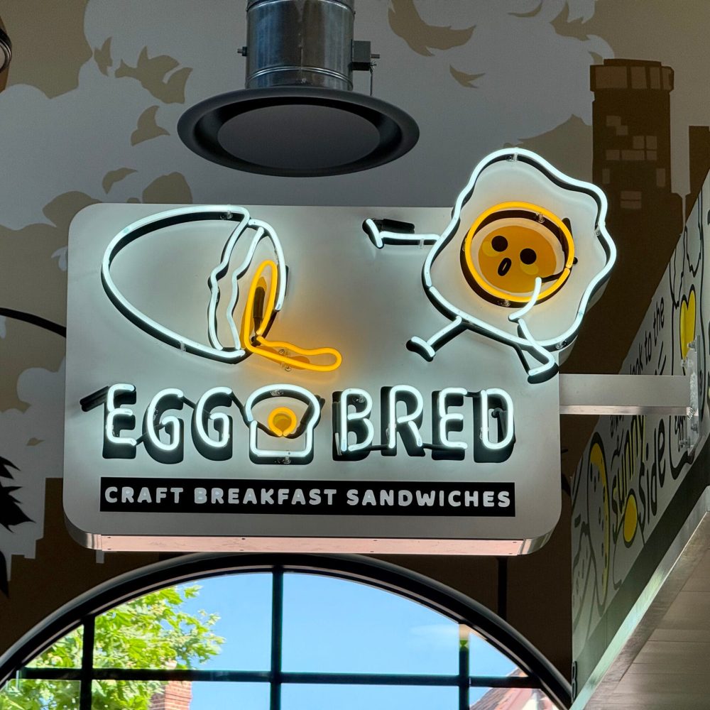 Custom bracket blade sign installed on a walkable retail block