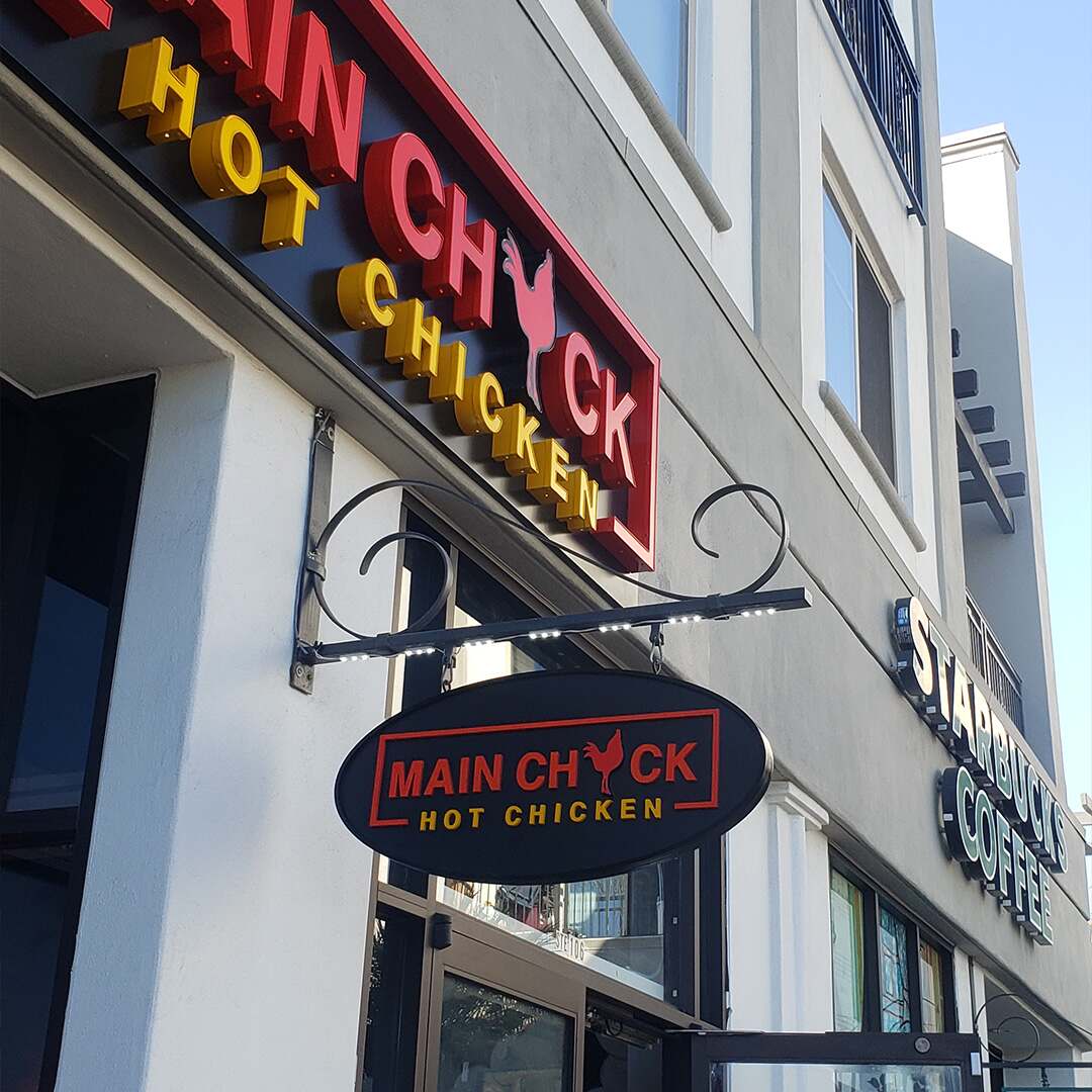 Illuminated Main Chick Hot Chicken blade cabinet sign mounted outside a Los Angeles restaurant