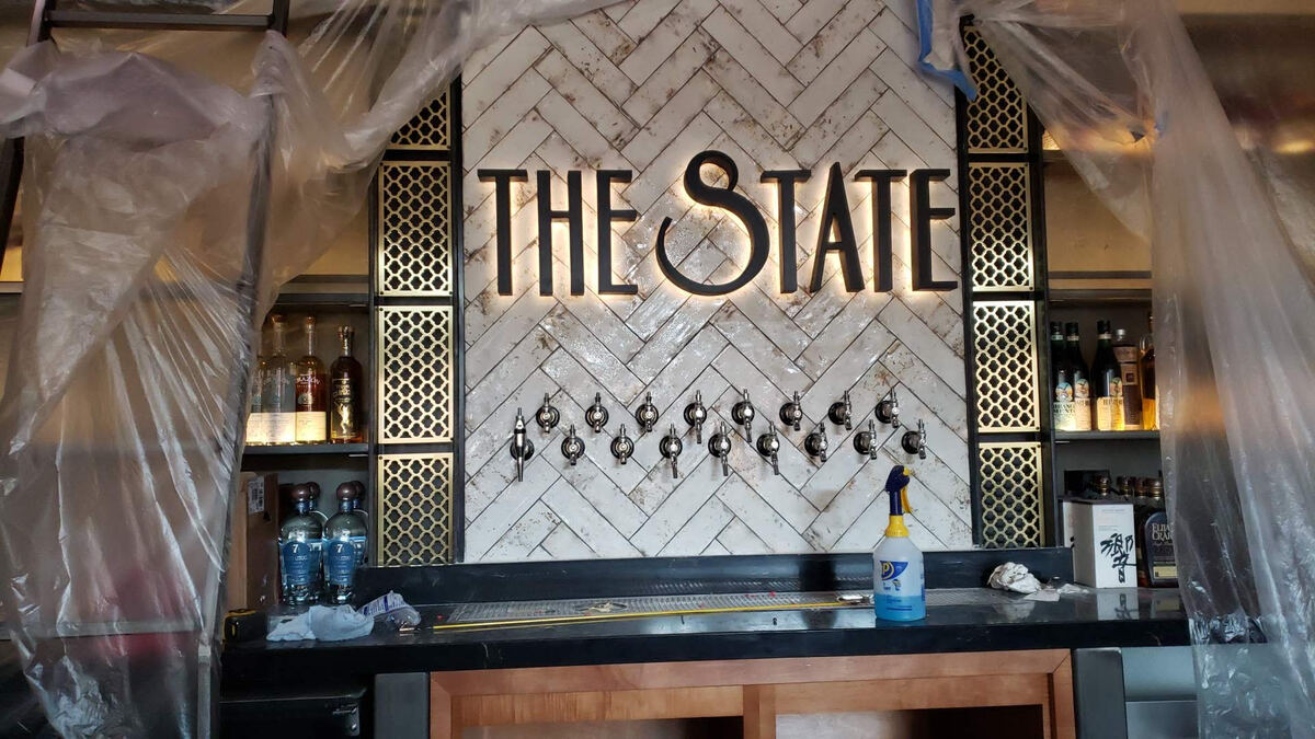 THE STATE back lit channel letters on a herringbone tile wall above the bar taps
