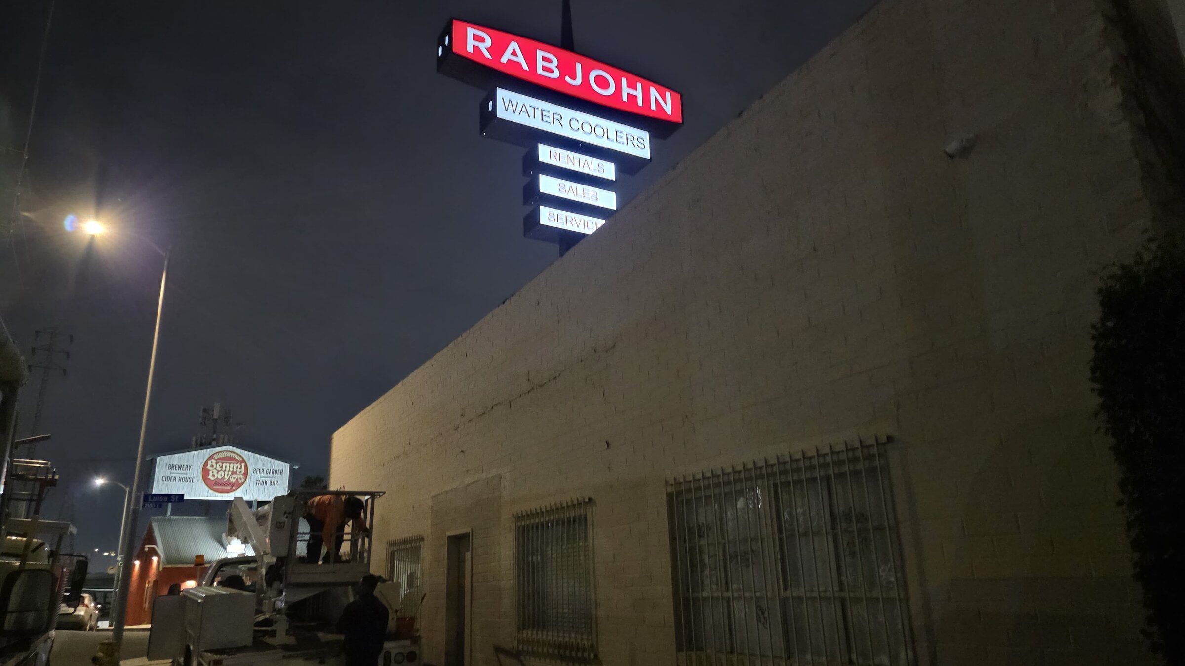 Illuminated aluminum cabinet sign glowing at night on a Los Angeles storefront