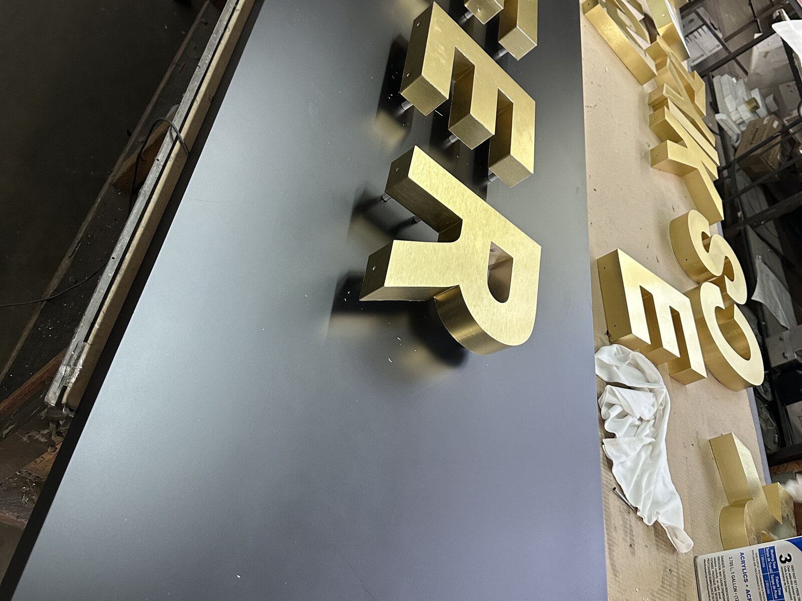 Reverse channel letters with a brushed gold aluminum face, viewed from above during fabrication