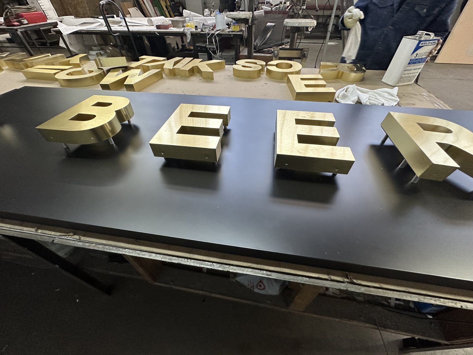 Reverse channel letters with a brushed metal face and halo glow on an architectural facade