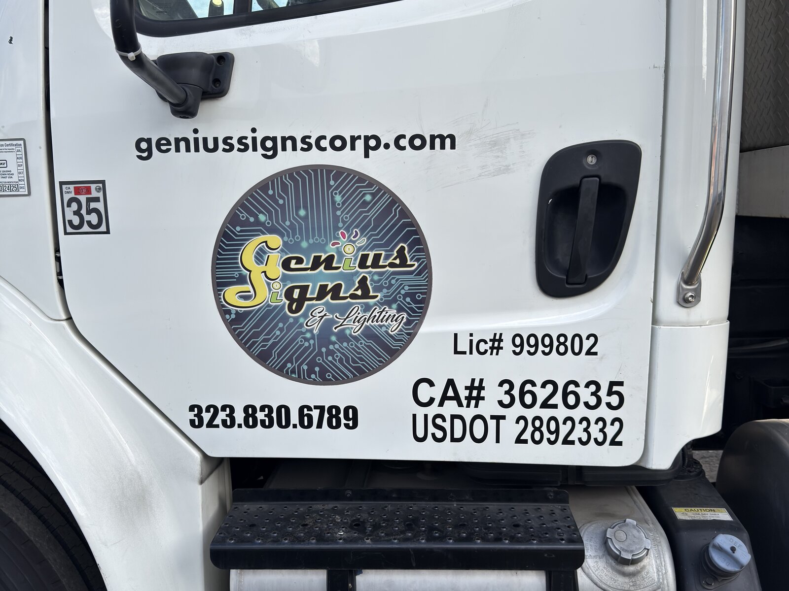 Genius Signs fleet truck with printed vinyl door lettering and license numbers