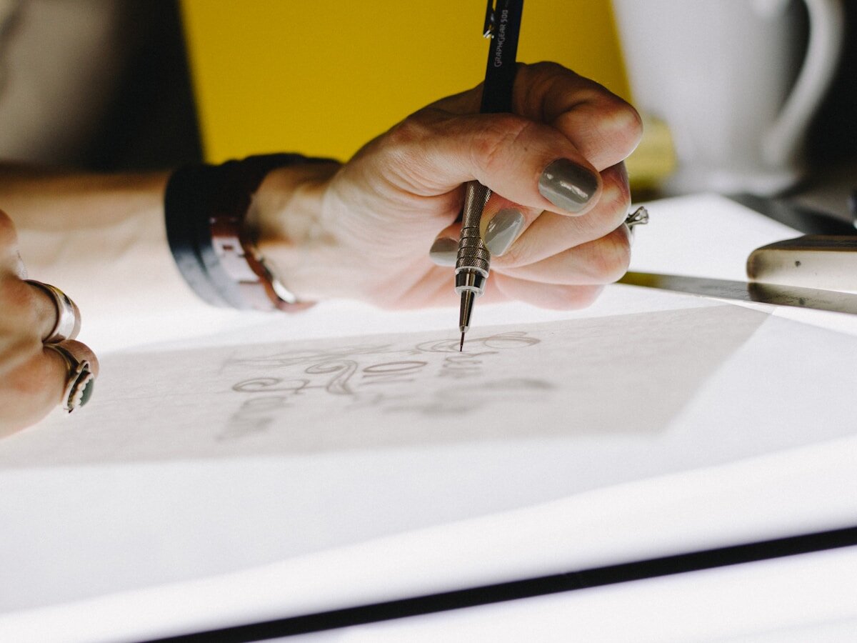 Designer hand-lettering typography on tracing paper with a mechanical pencil