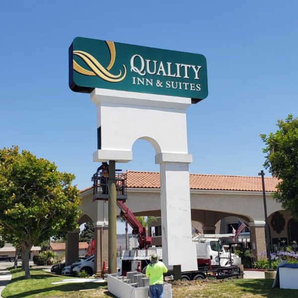 Installation of Quality Inn pole sign cover, enhancing visibility and brand recognition with precision.